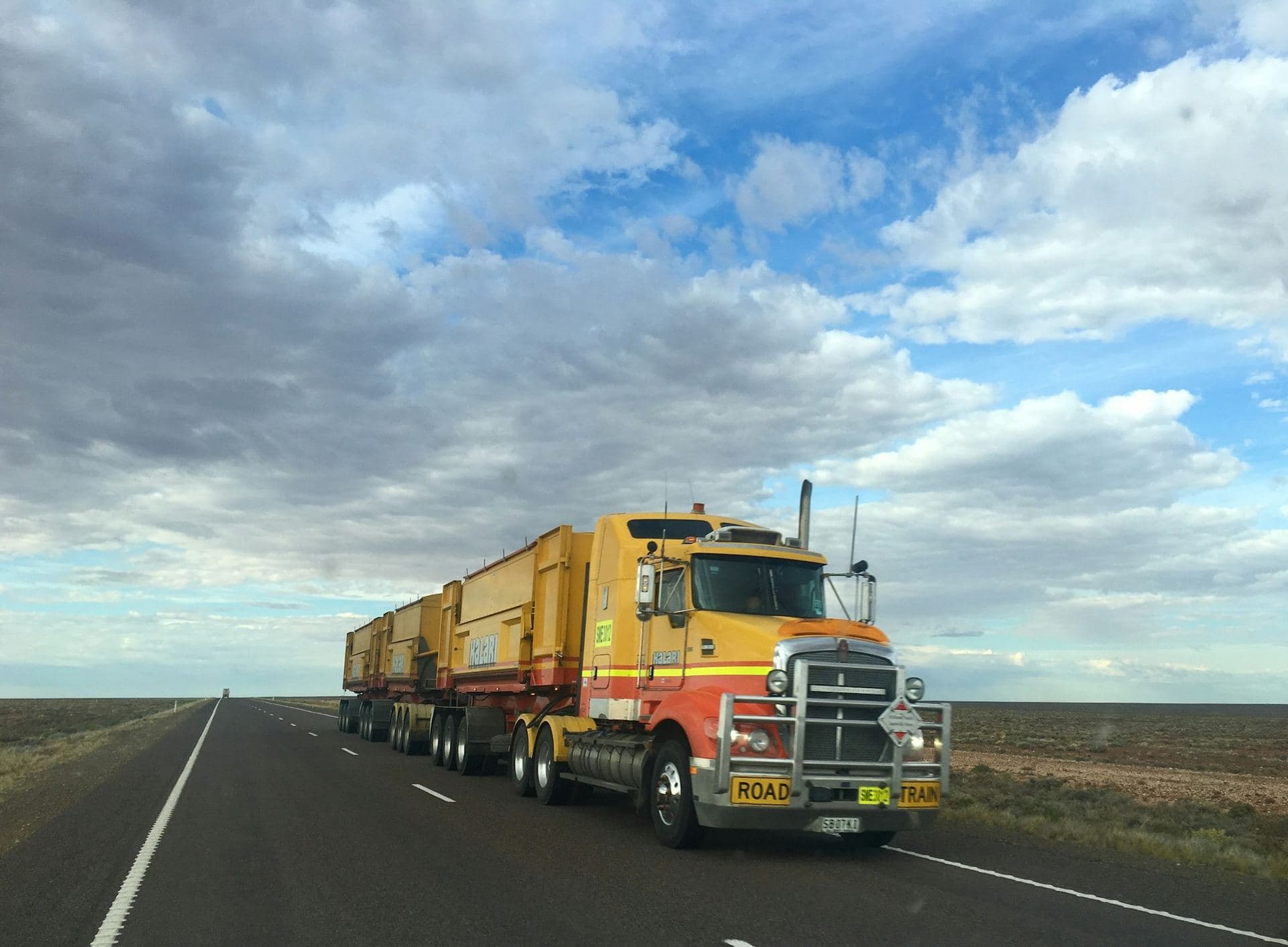 A long combination truck rolling across open plains